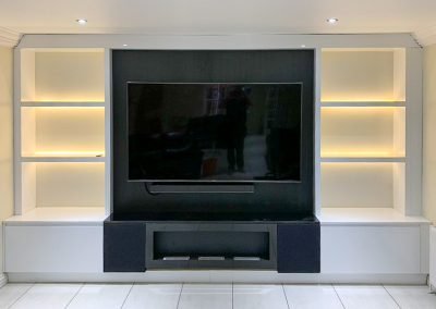 Bespoke media wall with a large TV recess, illuminated shelving and a fireplace