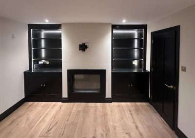 Dark bespoke media wall with a TV recess and glazed display cabinets