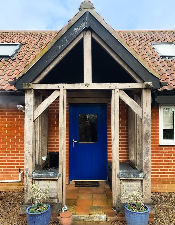 Oak-framed porch with a blue front door on a rendered house