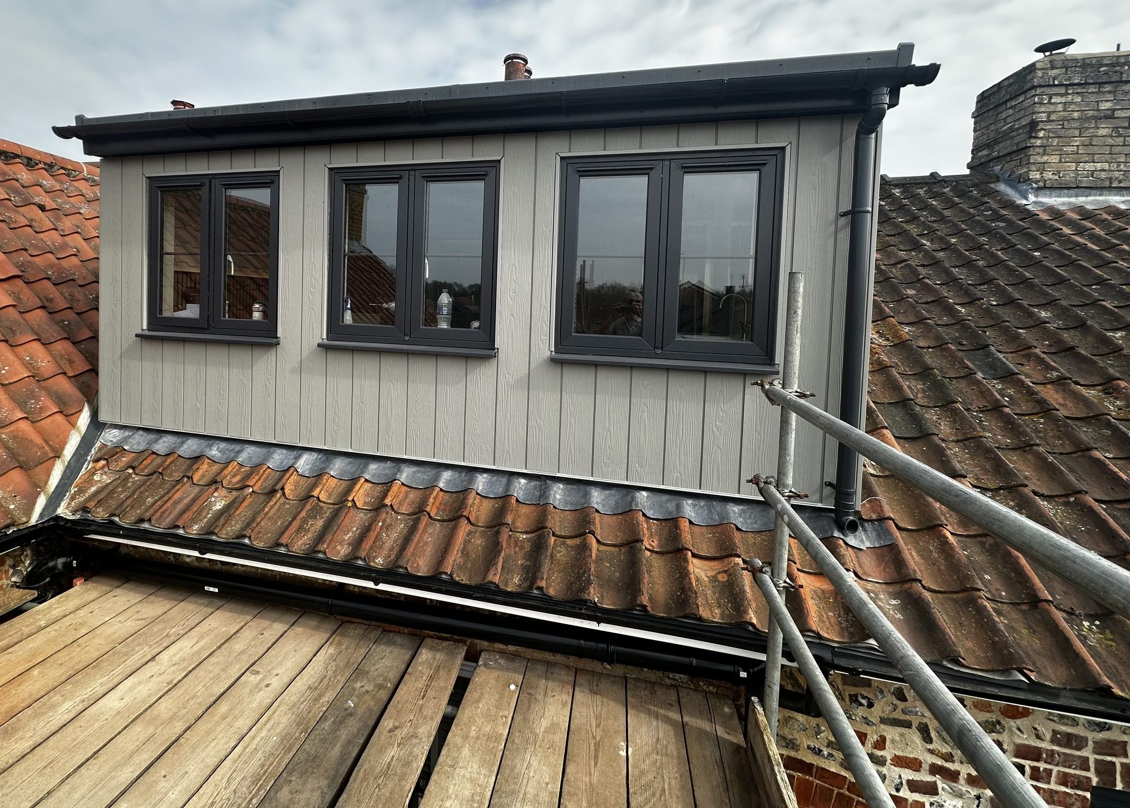 Newly built dormer with grey cladding and dark grey windows on a period property, one of the loft conversions we build around Stowmarket